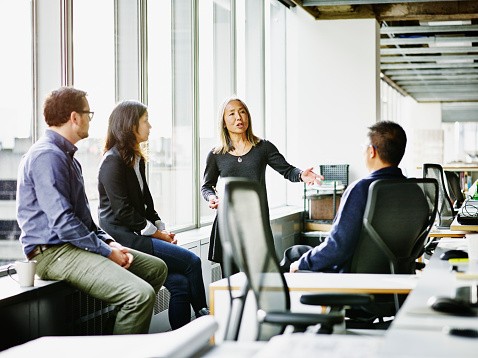 Mature businesswoman leading discussion during team meeting with coworkers in office